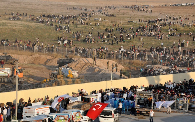 Syrian refugees from Tel Abyad (foreground) line up at the border crossing as the others wait behind the fences to cross into Turkey at the Akcakale border gate in Sanliurfa province, Turkey, June 14, 2015. Kurdish-led militia backed by U.S.-led air strikes fought Islamic State near a Syrian town at the Turkish border on Sunday, a monitoring group and a Kurdish official said, in an advance that has worried Turkey. Concerned about an expansion of Kurdish sway in Syria, Turkish President Tayyip Erdogan said Kurdish groups were taking over areas evacuated by Arabs and Turkmen, saying that might eventually threaten Turkey's borders. At least 13,000 people have fled into Turkey over the past week to escape the fighting near Tel Abyad. On Sunday, Turkish authorities reopened the border after a few days of closure, a security source said, adding that they expected as many as 10,000 people to come across. REUTERS/Kadir Celikcan TPX IMAGES OF THE DAY